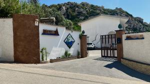 a white building with a gate and a mountain at Albatros Apartments in Licata
