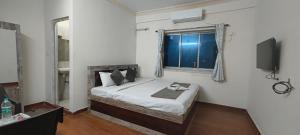 a bedroom with a bed with a window and a television at M A P Hotel in Nager Bazaar