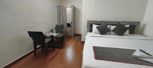 a bedroom with a bed and a desk with a chair at M A P Hotel in Nager Bazaar