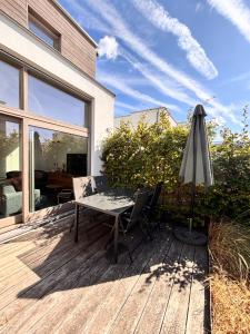 a table and an umbrella on a wooden deck at Maison Coxyde in Koksijde