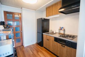 a kitchen with a black refrigerator and wooden cabinets at Numazu Royal Retreat 201 in Numazu