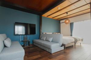 a bedroom with a bed and a couch and a tv at Numazu Royal Retreat 201 in Numazu