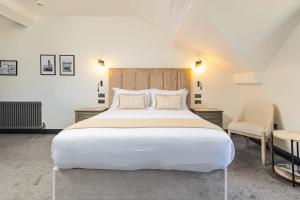 a bedroom with a large white bed and two chairs at Falcon's Nest Hotel in Port Erin