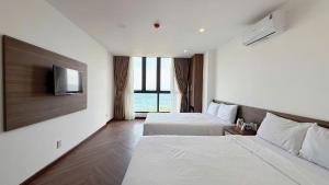 a hotel room with two beds and a flat screen tv at Aqua Hotel & Spa Managed by PD in Nha Trang +19 photos