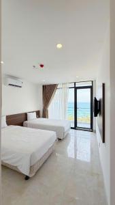 two beds in a bedroom with a view of the ocean at Aqua Hotel & Spa Managed by PD in Nha Trang