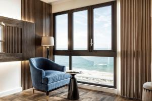 a room with a blue chair and a window with the ocean at Aqua Hotel & Spa Managed by PD in Nha Trang