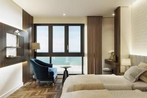 a bedroom with a bed and a chair and a window at Aqua Hotel & Spa Managed by PD in Nha Trang
