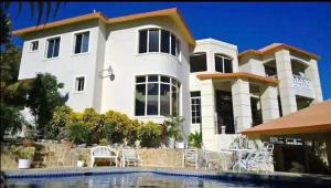 a large white house with a pool in front of it at Villa La Dueña in San Felipe de Puerto Plata