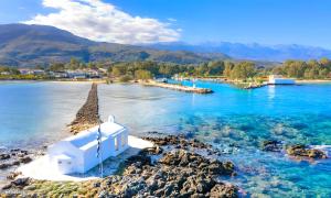 a white chapel on the shore of a body of water at Cretan Breeze Villa Heated Pool in Dhrámia +19 photos