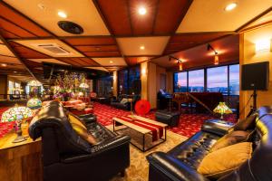 a living room with leather couches and a television at Seaside Hotel Mimatsu Ooetei in Beppu