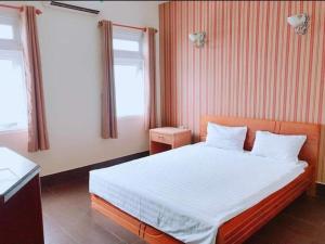 a bedroom with a bed with white sheets and two windows at RUBY HOTEL in Cà Mau