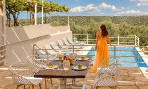 a woman in an orange dress is standing on a balcony at Cretan Breeze Villa Heated Pool in Dhrámia