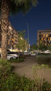 a parking lot with a palm tree and buildings at night at شقة غرفتين وصالة مريحة in Jeddah