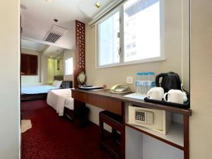 ein Zimmer mit einem Bett und einem Schreibtisch mit Mikrowelle in der Unterkunft Oriental Lander Hotel in Hongkong + 87 Fotos