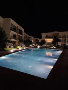 a large swimming pool in front of a building at night at Blue water house in Tamaris