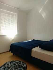 a bedroom with a blue bed and a window at Apartman Lana in Klimno