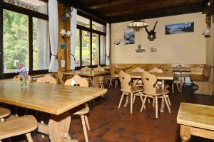 a restaurant with wooden tables and chairs and windows at Hôtel Grand-Combin in Fionnay