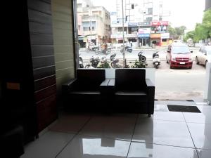 a black couch sitting in front of a window at Hotel Jasmine in Ahmedabad