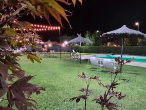 a yard with chairs and umbrellas and a swimming pool at night at El Linar in Burgohondo +20 photos