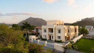 a large white house with a hill in the background at Chez Lavania - A Boutique Stay in Udaipur