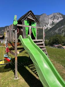 a playground with a green slide and a house at Apartment Fidelia in Vandans