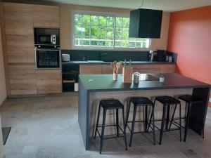 a kitchen with a large island with four bar stools at Domaine Cosme in Le Noyer-en-Ouche