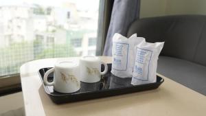 a tray with two mugs and two cups on a table at Hotel Yagnik Inn in Rajkot