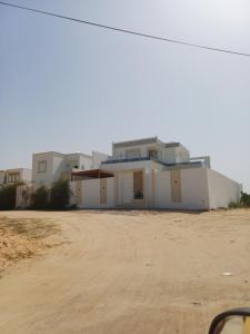 a large white house on a dirt road at Villa baya in Djerba