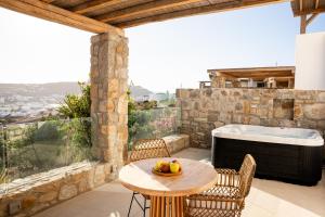 a patio with a table and chairs and a tub at Due Mari Mykonos in Agios Ioannis Mykonos