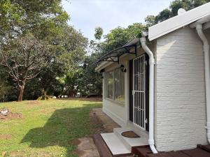 a white building with a door and a yard at 2 bedrooms Ngubelanga Stays in Margate