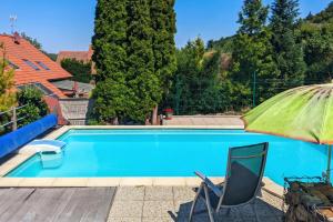 a blue swimming pool with a chair and an umbrella at Guest House KRISTI in Tuchoměřice