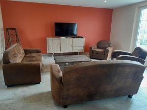 a living room with leather furniture and a flat screen tv at Domaine Cosme in Le Noyer-en-Ouche