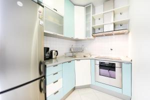 a small kitchen with blue cabinets and white appliances at Jelena - Spacious Sea View Apartment - Old Town Zadar in Zadar