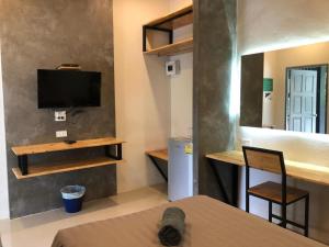 a living room with a tv and a table with a chair at CoCo Tree Resort in Thap Sakae