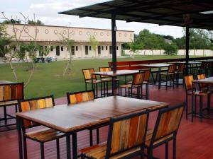 an outdoor patio with tables and chairs and a field at Surintara Resort in Surin