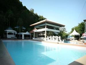 a swimming pool with white chairs and a building at Splash Mountain Resort & Hotel in Forestry