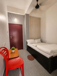 a small room with a bed and a red chair at White Lily in Guwahati +19 photos