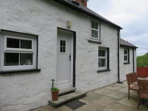 Casa blanca con puerta y ventanas blancas en The Coach House Self Catering Apartments en Glenariff