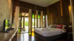 a bedroom with a bed and a television in it at Chababaancham Resort in Amphawa
