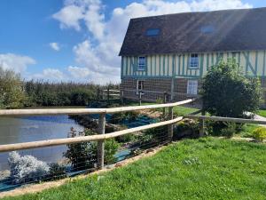 a house with a fence next to a pond at Domaine Cosme in Le Noyer-en-Ouche