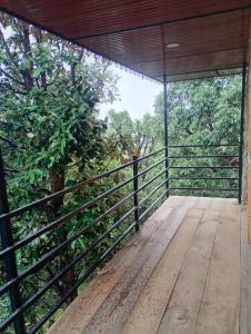 a wooden porch with a fence and a tree at DnD cottages in Mandi