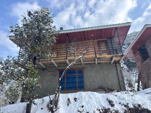 a house with a balcony in the snow at DnD cottages in Mandi