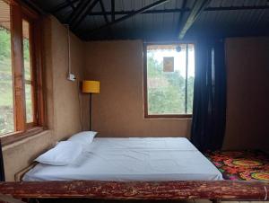 a bed in a room with a window at DnD cottages in Mandi