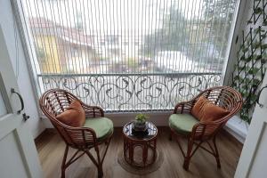 a balcony with two chairs and a table and a large window at Shalom in Colva