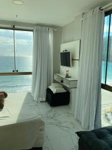 a bedroom with a bed and a large window at Loft da Prainha in Arraial do Cabo