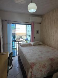 a bedroom with a bed and a window with a balcony at Pousada de Isa in Palhoça