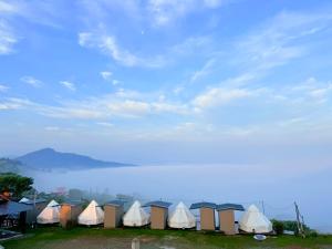 a row of tents in a field next to a body of water at Heaven Khaokho (เฮฟเว่น) in Khao Kho +13 photos