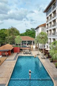 a person standing in a swimming pool next to a building at Le Monte Khao Yai in Mu Si