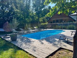 a swimming pool with a wooden deck next to a house at Ferienwohnungen Brenner einchecken und wohlfühlen in Langenbernsdorf