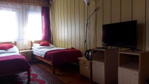 a bedroom with two beds and a flat screen tv at Nad Bałtykiem in Mrzeżyno